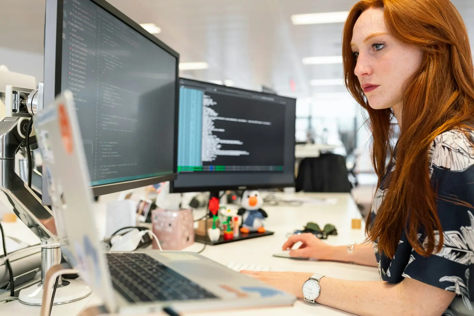 A support agent at a desk with a laptop and a second monitor